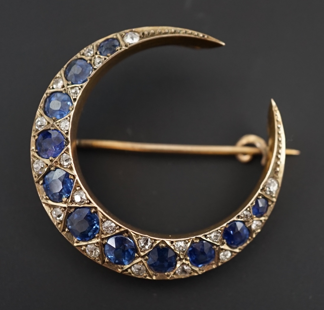 An early 20th century gold, graduated sapphire and diamond cluster set crescent brooch